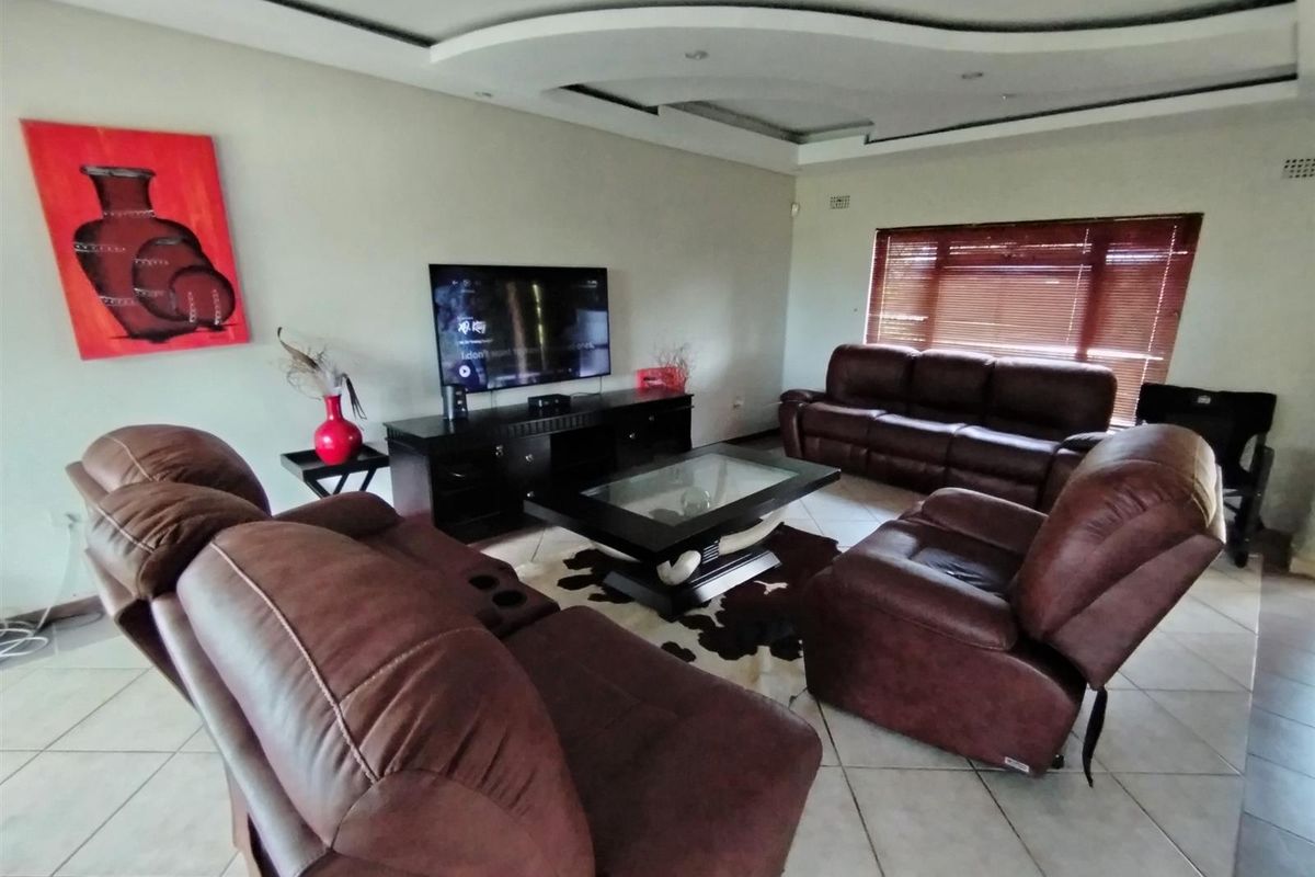 Spacious living room featuring a decorative recessed ceiling with integrated lighting and tiled flooring.