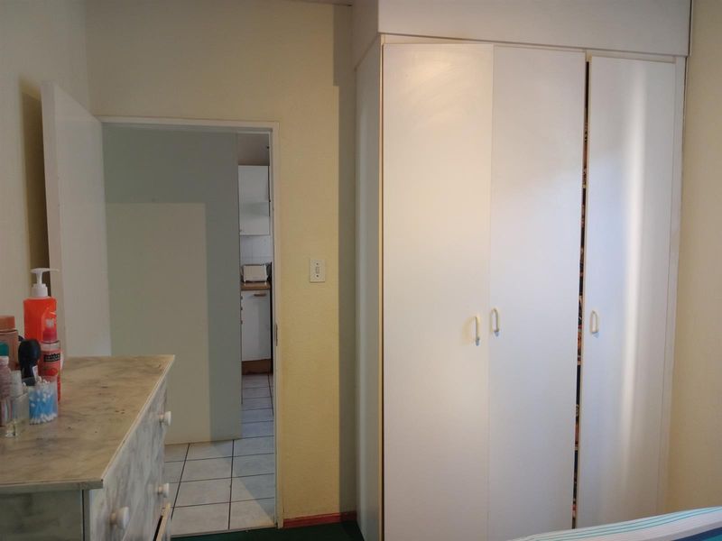 A bedroom featuring built-in white cabinetry and a doorway leading to an adjacent tiled kitchen area.