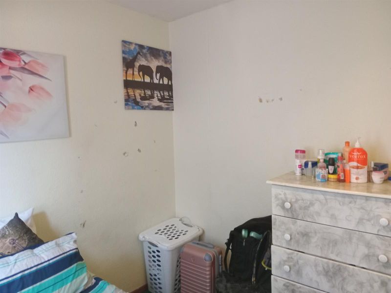 A bedroom interior featuring plain walls with visible surface imperfections and scuff marks, requiring minor cosmetic repairs.