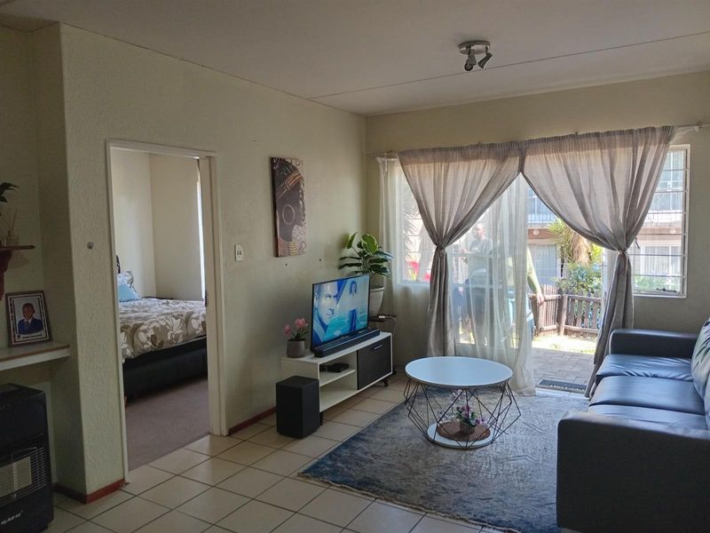 A living room featuring tiled flooring, a sliding glass door leading to an outdoor area, and an adjacent bedroom entrance.