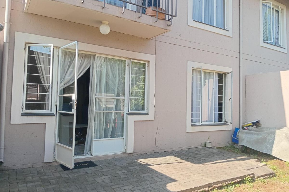 Ground floor patio area with paved flooring, security gates, and access to the interior living space.