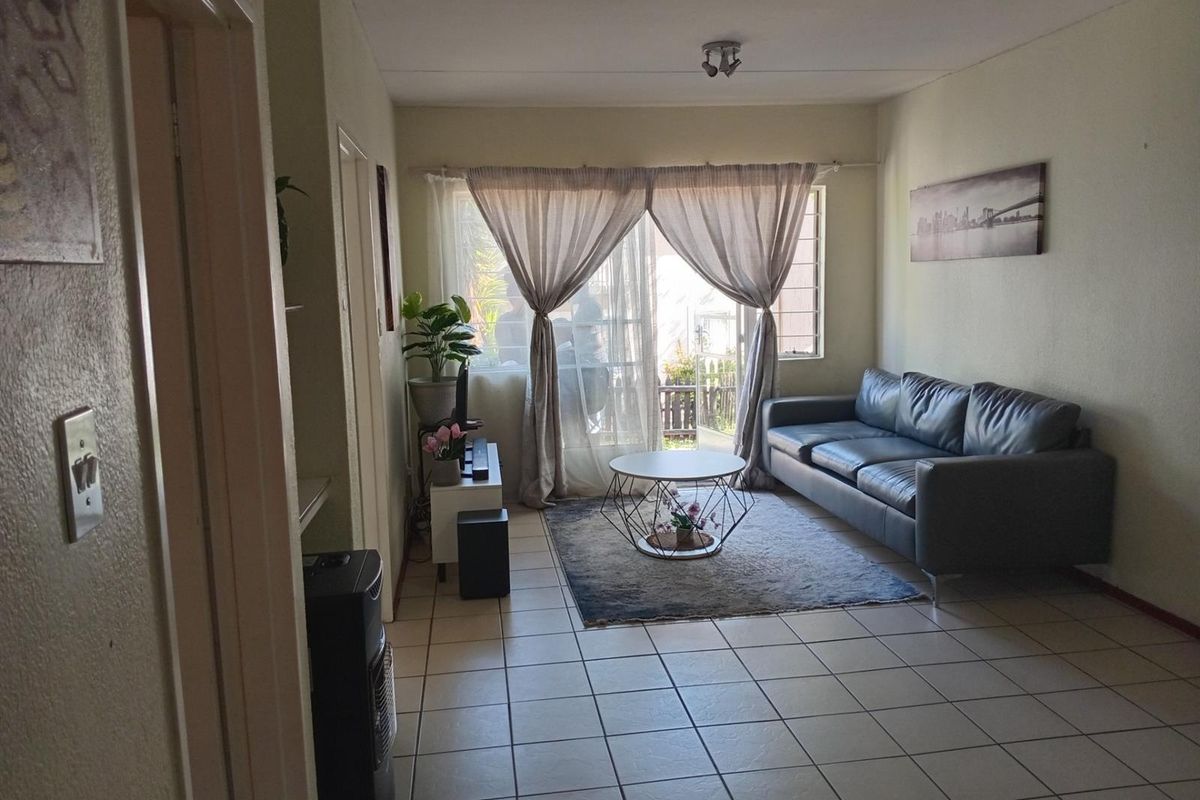 A functional living room featuring tiled flooring, a sliding glass door leading to an outdoor area, and neutral wall finishes.
