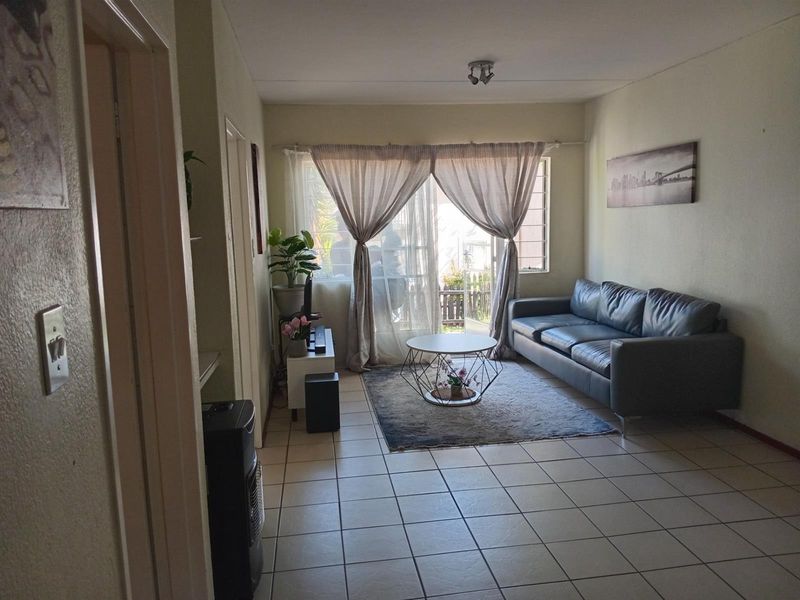 A functional living room featuring tiled flooring, a sliding glass door leading to an outdoor area, and neutral wall finishes.