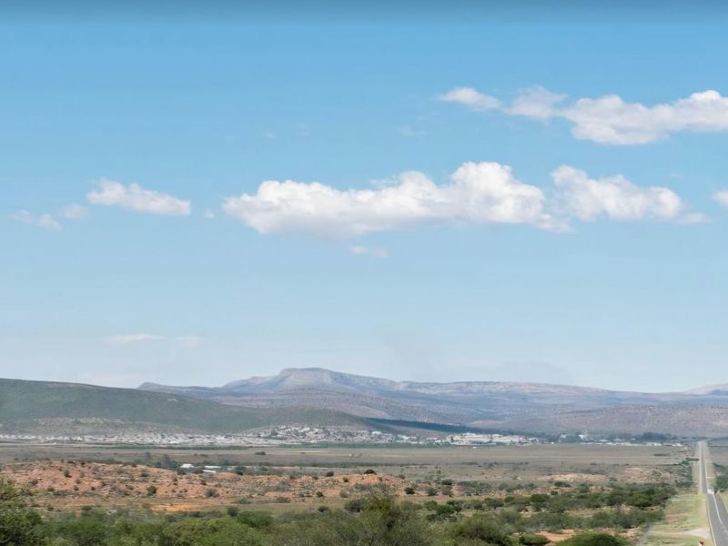 A wide-angle landscape view showcasing the expansive natural terrain, distant mountain ranges, and a clear horizon under a bright blue sky.