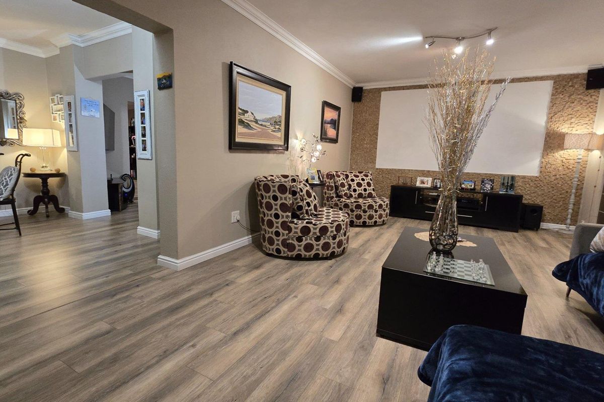 Spacious living area featuring modern wood-look laminate flooring, crown molding, and a textured feature wall, creating a comfortable and inviting atmosphere.