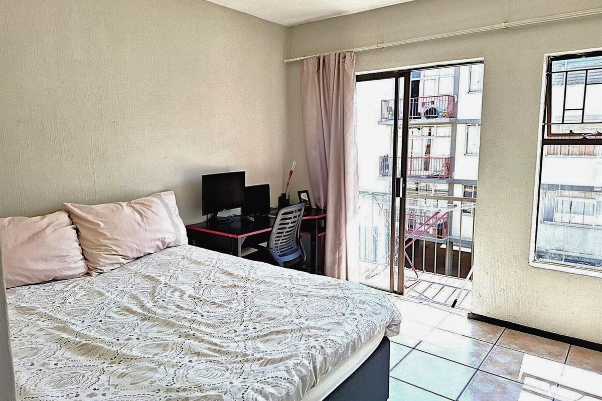 A bedroom featuring tiled flooring and a sliding glass door that opens onto a small balcony.