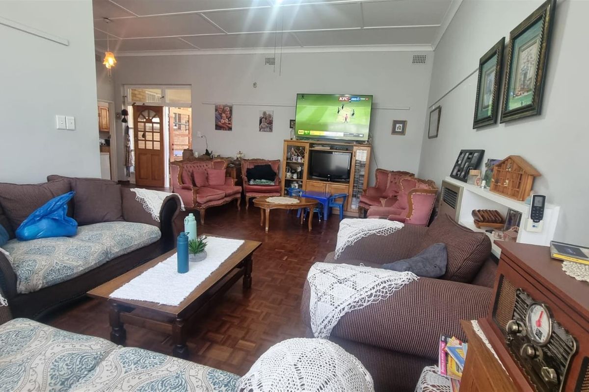 Spacious living room featuring traditional parquet flooring, high ceilings, and direct access to the kitchen area.