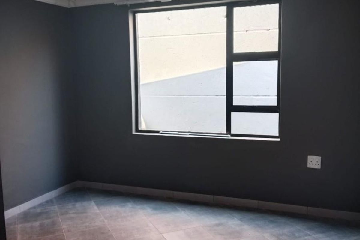 An empty bedroom featuring dark grey walls, tiled flooring, and a glossy ceiling finish with a large aluminium-framed window.