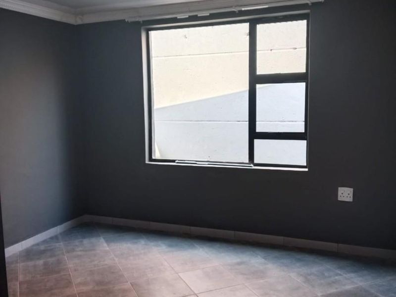 An empty bedroom featuring dark grey walls, tiled flooring, and a glossy ceiling finish with a large aluminium-framed window.