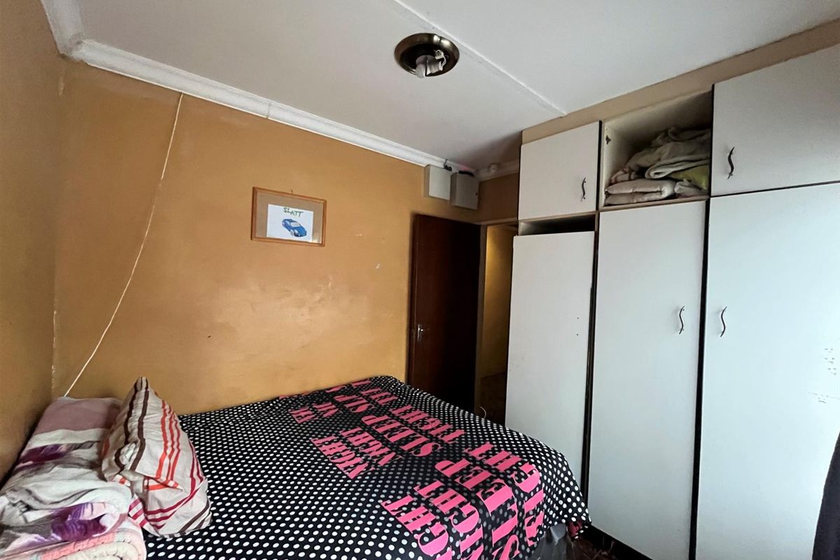 A bedroom featuring built-in cabinetry and tiled flooring, requiring cosmetic updates to the walls and ceiling.