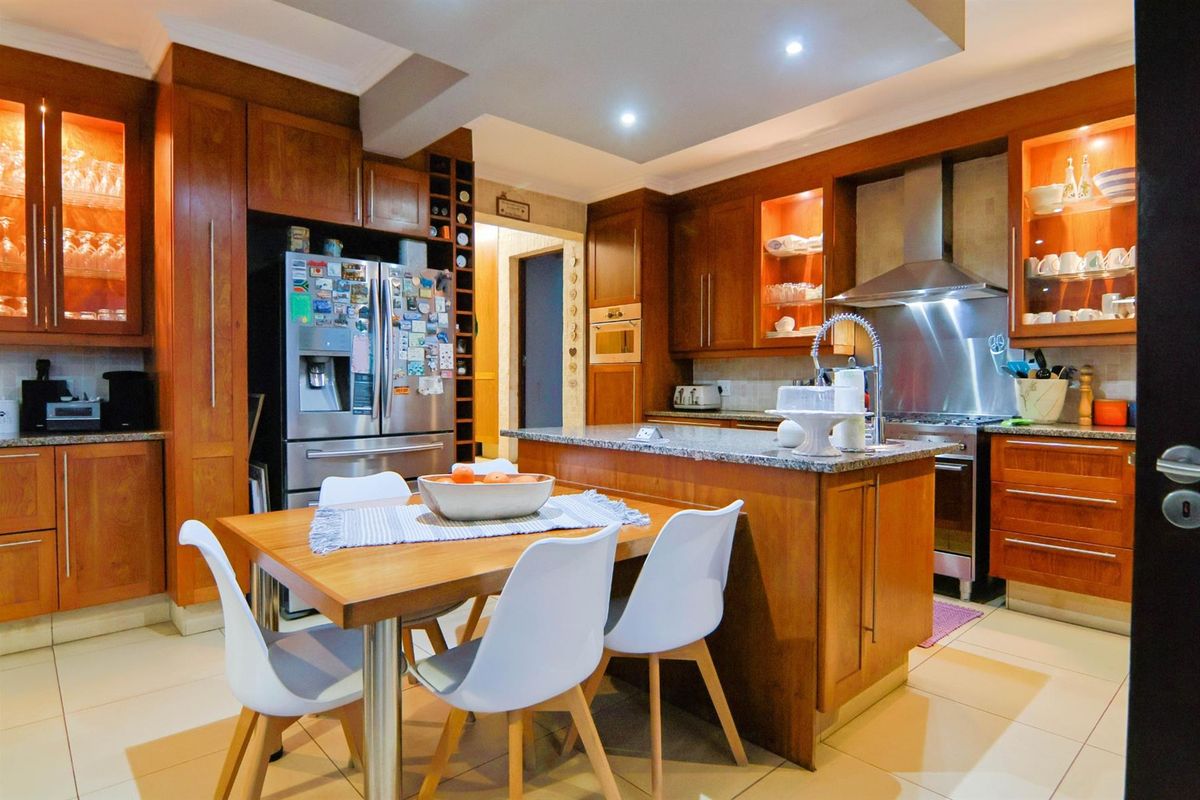 A well-appointed kitchen featuring warm wooden cabinetry, granite countertops, a central island, and integrated stainless steel appliances with recessed lighting.
