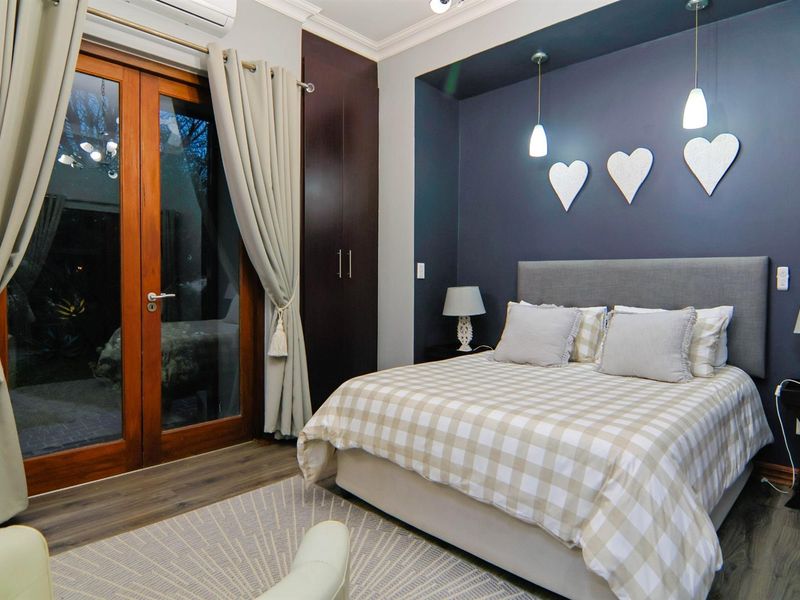 A well-appointed bedroom featuring laminate flooring, built-in cupboards, and wooden framed glass doors providing direct access to the exterior.