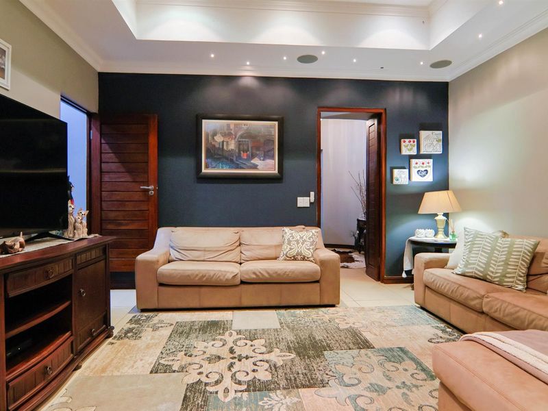 A well-maintained living room featuring a recessed ceiling with integrated downlights, ceiling speakers, and tiled flooring, creating a comfortable and functional space.