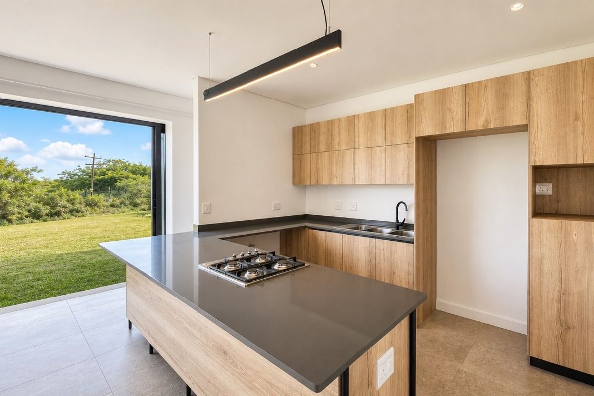 Modern kitchen featuring light wood cabinetry, stone countertops, a central gas hob, and direct access to the garden through large sliding glass doors.