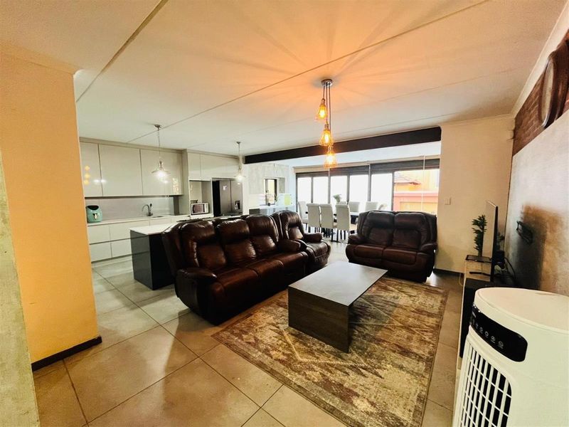 Open-plan living area featuring a modern kitchen with sleek cabinetry, tiled flooring, and a seamless flow to the dining and lounge spaces.