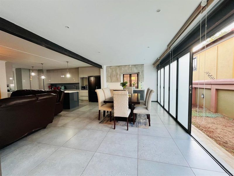 Spacious open-plan living and dining area featuring large sliding glass doors that open to the side yard, complemented by a modern kitchen.