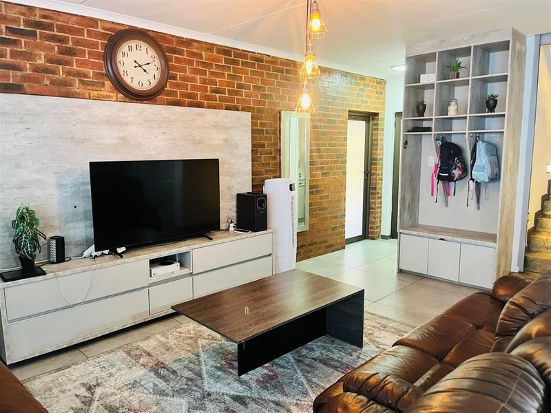 Living room featuring an exposed brick feature wall, built-in cabinetry, and tiled flooring.