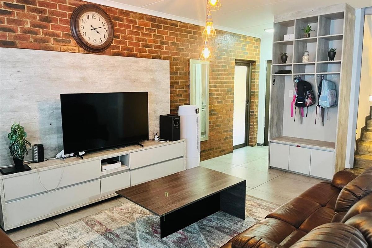 Living room featuring an exposed brick feature wall, built-in cabinetry, and tiled flooring.
