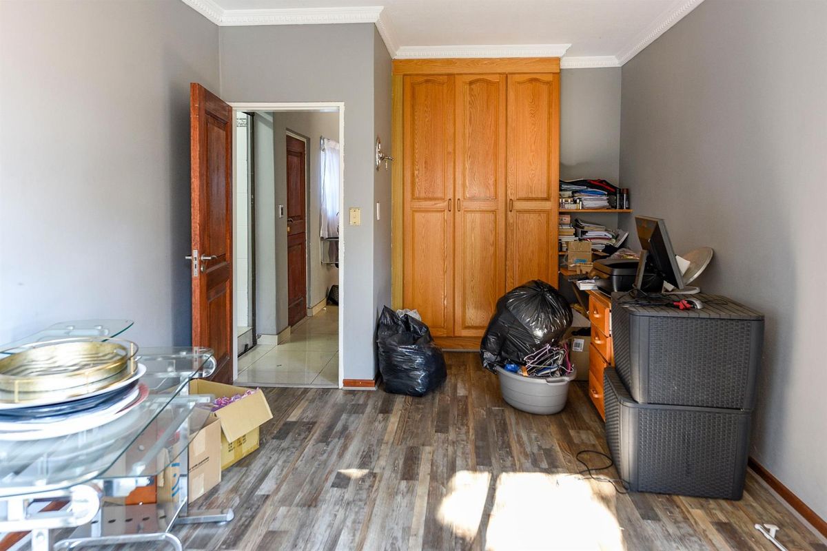 A bedroom featuring laminate flooring, crown molding, and a built-in wooden wardrobe, with direct access to an adjoining room.