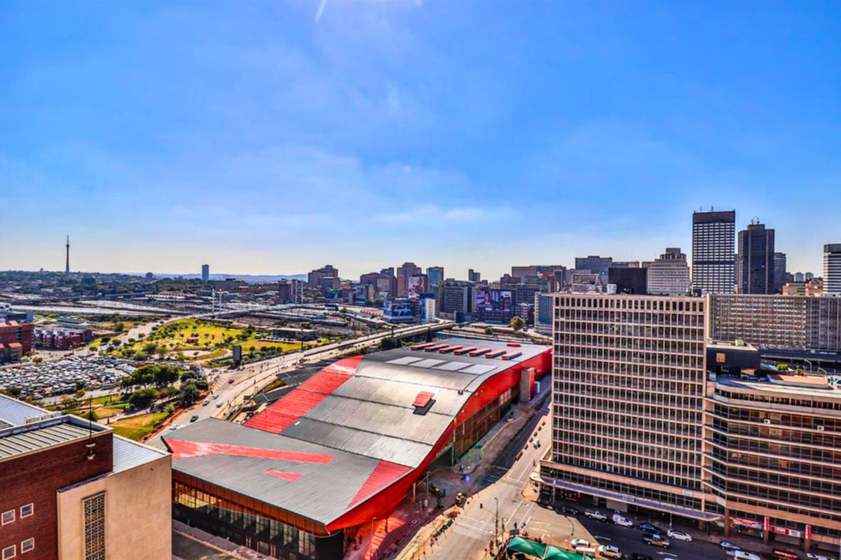 Elevated aerial view overlooking the city skyline, featuring urban infrastructure, commercial buildings, and surrounding road networks.