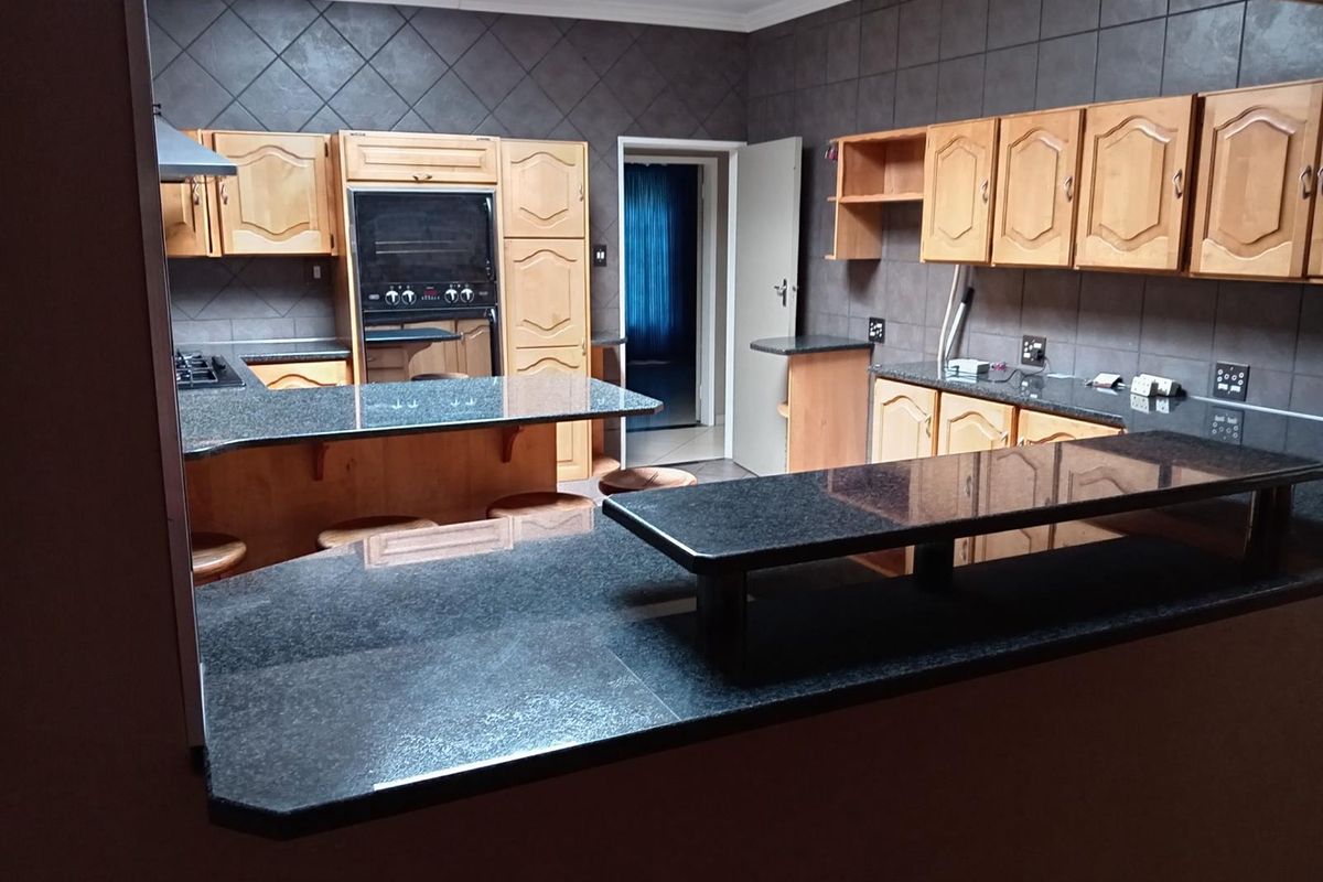 A functional kitchen featuring dark granite countertops, wooden cabinetry, and a breakfast bar, providing ample workspace and storage.