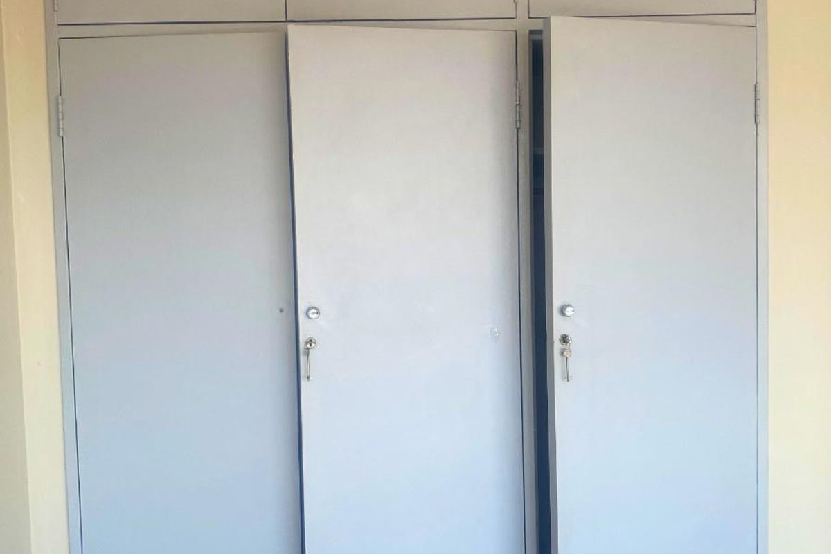 A bedroom featuring built-in floor-to-ceiling storage cupboards with light grey painted doors.