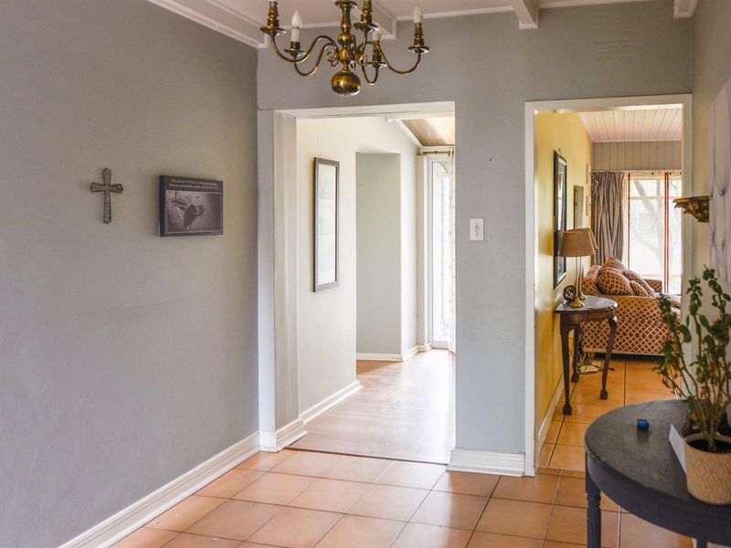 A functional hallway featuring ceramic floor tiles, coved ceilings, and access to adjacent living spaces.