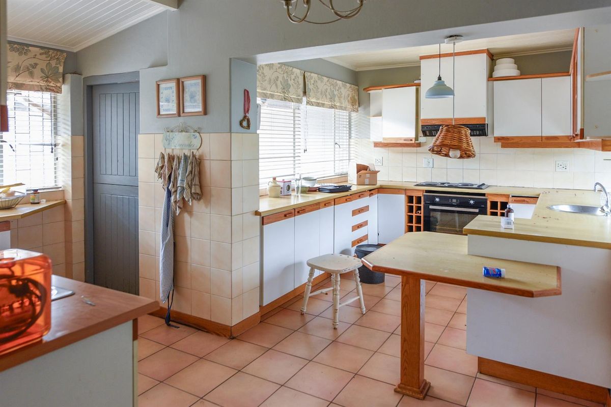 A functional kitchen featuring built-in cabinetry, tiled flooring, and a tiled splashback, offering a practical layout with integrated oven and hob.