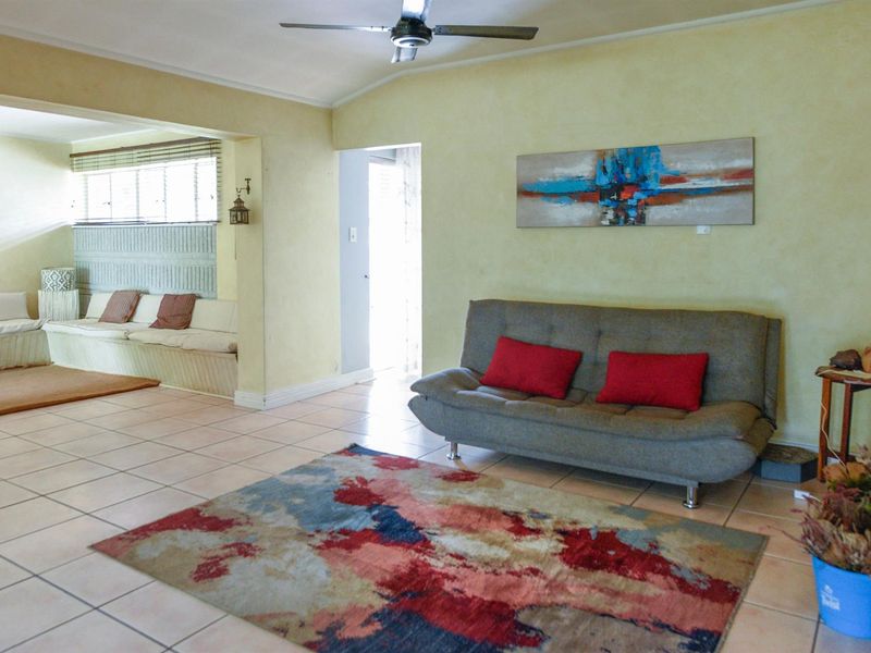 Open plan living area featuring tiled flooring, a ceiling fan, and a built-in bench seating area in the adjacent space.
