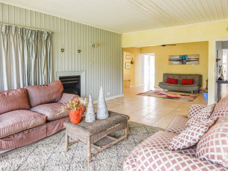Spacious living area featuring tiled flooring, a built-in fireplace, and vertical wall paneling, with an open-plan flow to the adjacent room.