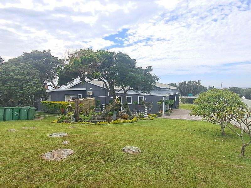 A view of the rear exterior of the house, featuring a well-maintained lawn, landscaped garden, and a white picket fence.