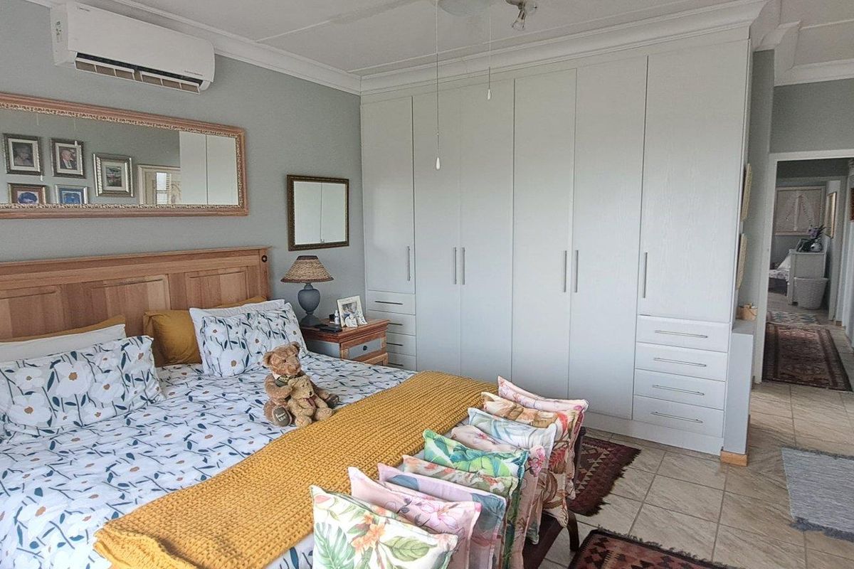 Spacious bedroom featuring extensive built-in cabinetry, tiled flooring, and a wall-mounted air conditioning unit.