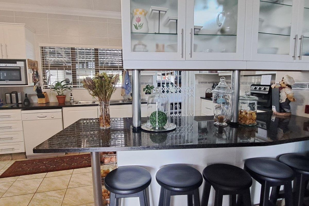 A well-maintained kitchen featuring granite countertops, a breakfast bar, built-in appliances, and ample cabinetry with glass-front display sections.