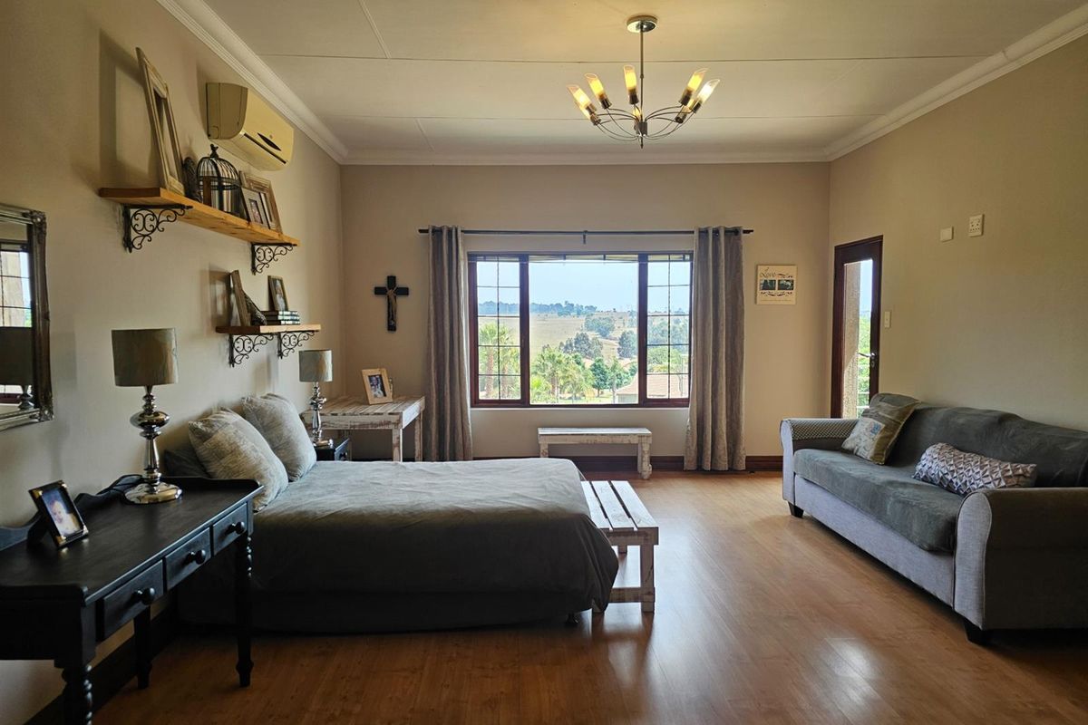 Spacious bedroom featuring laminate flooring, a large window with scenic views, and a wall-mounted air conditioning unit.