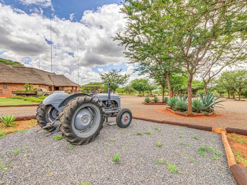 A view of the property exterior featuring a traditional thatched roof building, gravel driveway, and landscaped garden area.