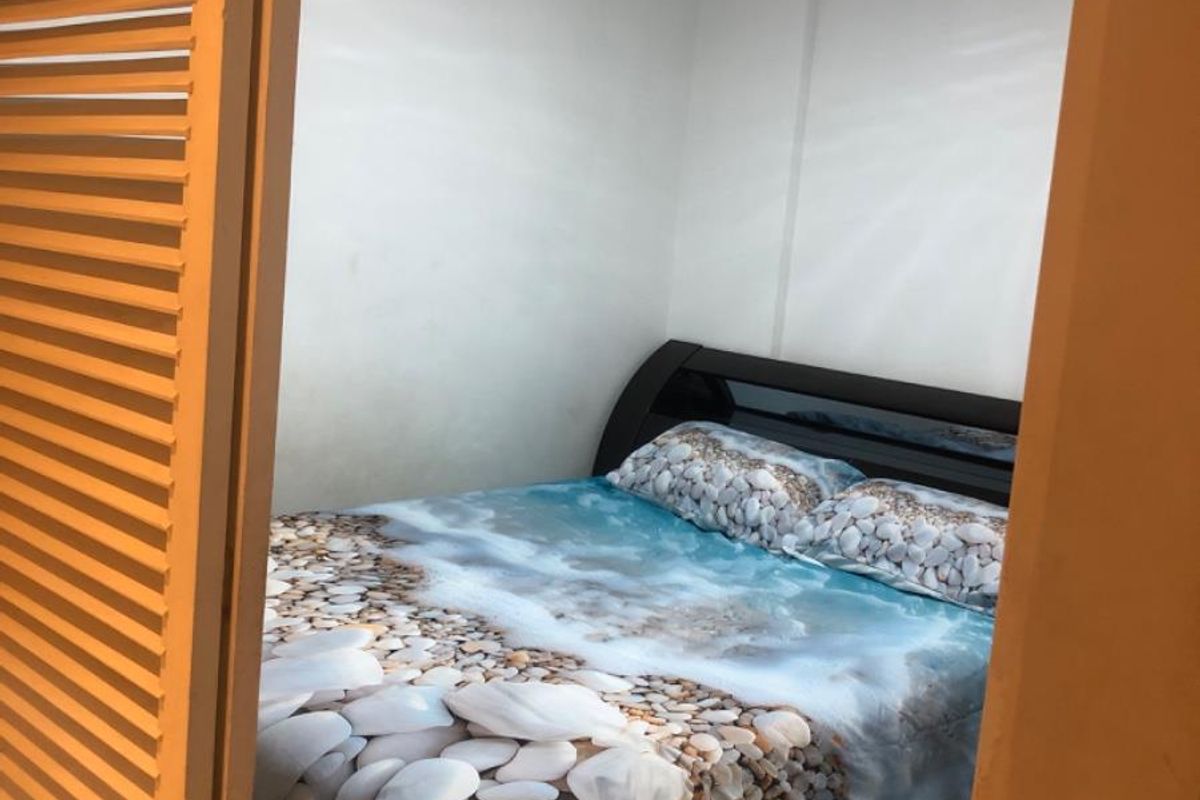A compact bedroom featuring a built-in louvered closet door and a central ceiling light fixture.