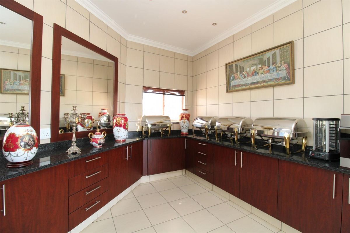 A functional kitchen area featuring dark wood cabinetry, granite countertops, and full-height wall tiling, suitable for food preparation and service.