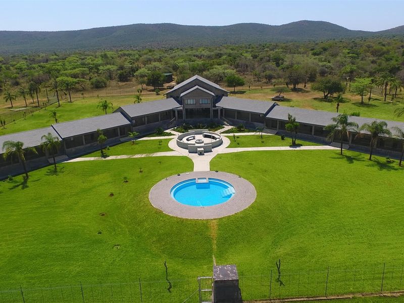 Aerial view of a sprawling farm estate featuring a large central residence, manicured lawns, a circular swimming pool, and a fire pit area.