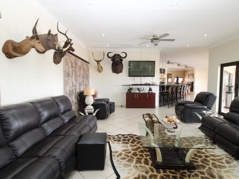 Spacious open-plan living area featuring tiled flooring, recessed ceiling lighting, and a ceiling fan, seamlessly connecting to the dining and kitchen space.