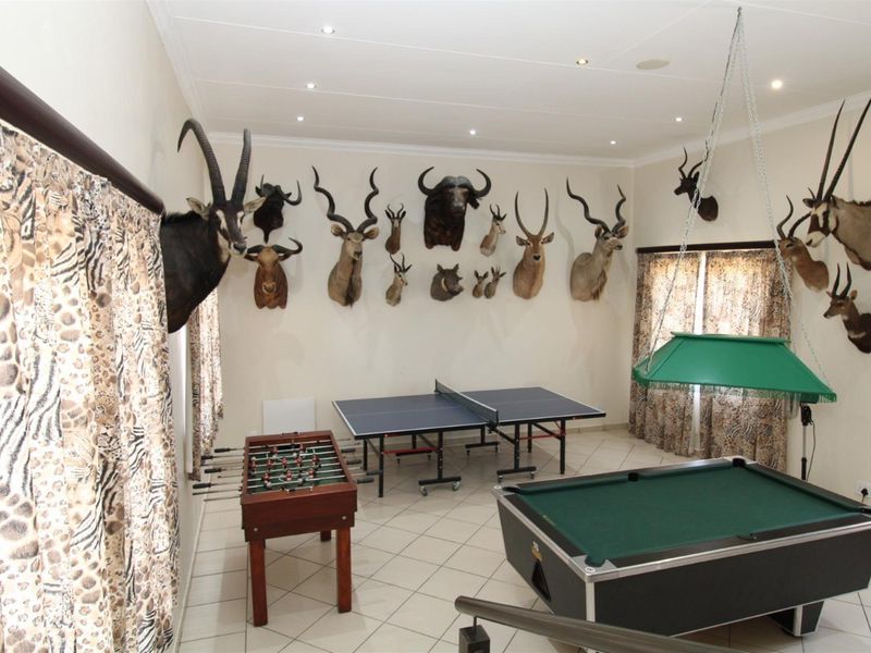 A spacious entertainment room featuring tiled flooring, recessed ceiling lighting, and ample wall space, currently utilized as a games room.