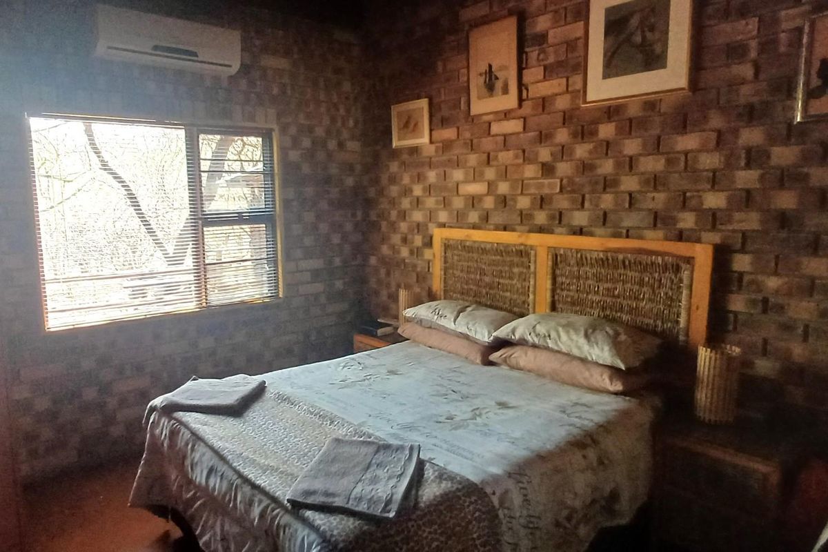 A bedroom featuring exposed brick walls, a split-system air conditioner, and a window with fitted blinds.