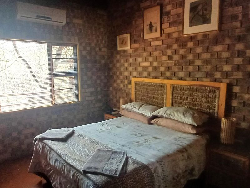 A bedroom featuring exposed brick walls, a split-system air conditioner, and a window with fitted blinds.