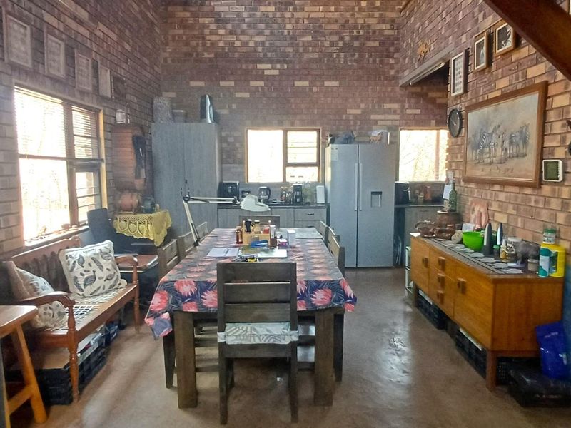 Open-plan living and kitchen area featuring rustic exposed brick walls, timber ceiling beams, and durable concrete flooring.