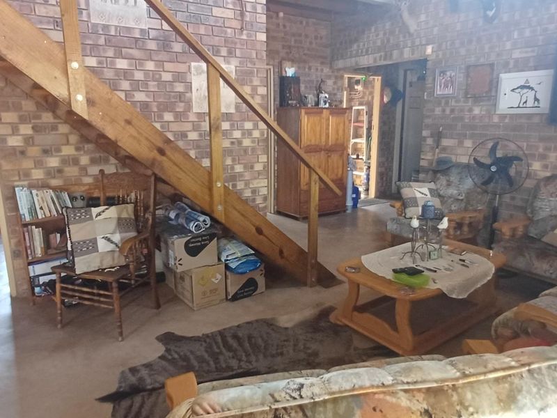 A rustic living room featuring exposed brick walls, concrete flooring, and a wooden staircase with a matching balustrade.