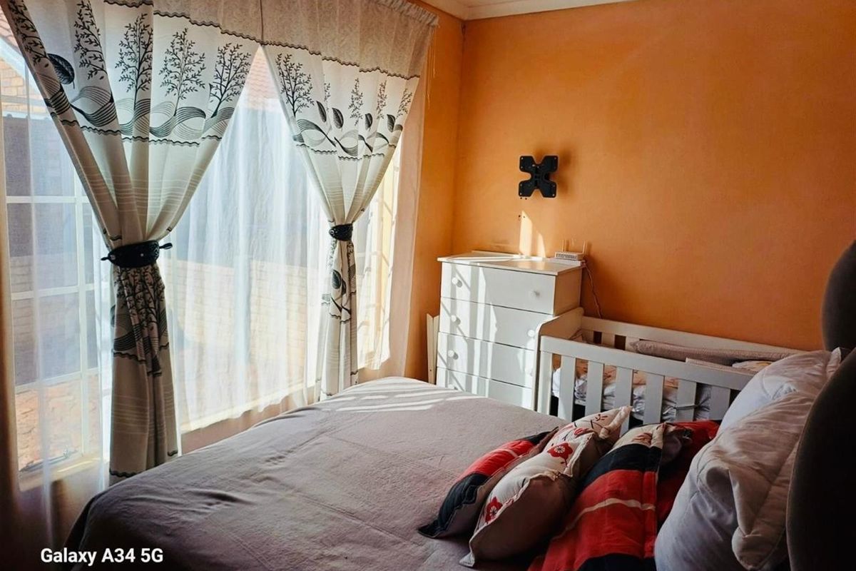 A bedroom featuring a large window with curtains, painted walls, and a wall-mounted television bracket.