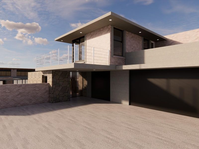 A modern residential exterior featuring a brick and stone facade, a balcony with railing, and a double garage entrance.