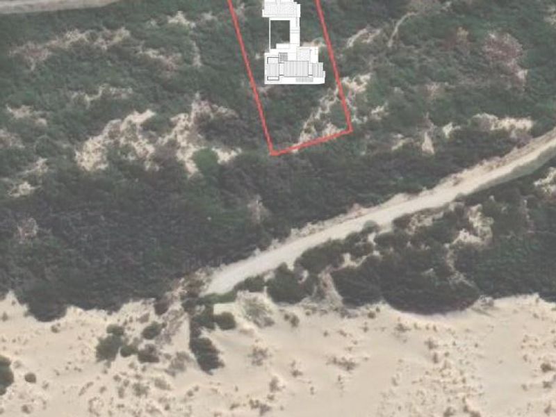 Aerial view of a vacant residential plot situated in a coastal landscape with native vegetation and proximity to the beach.