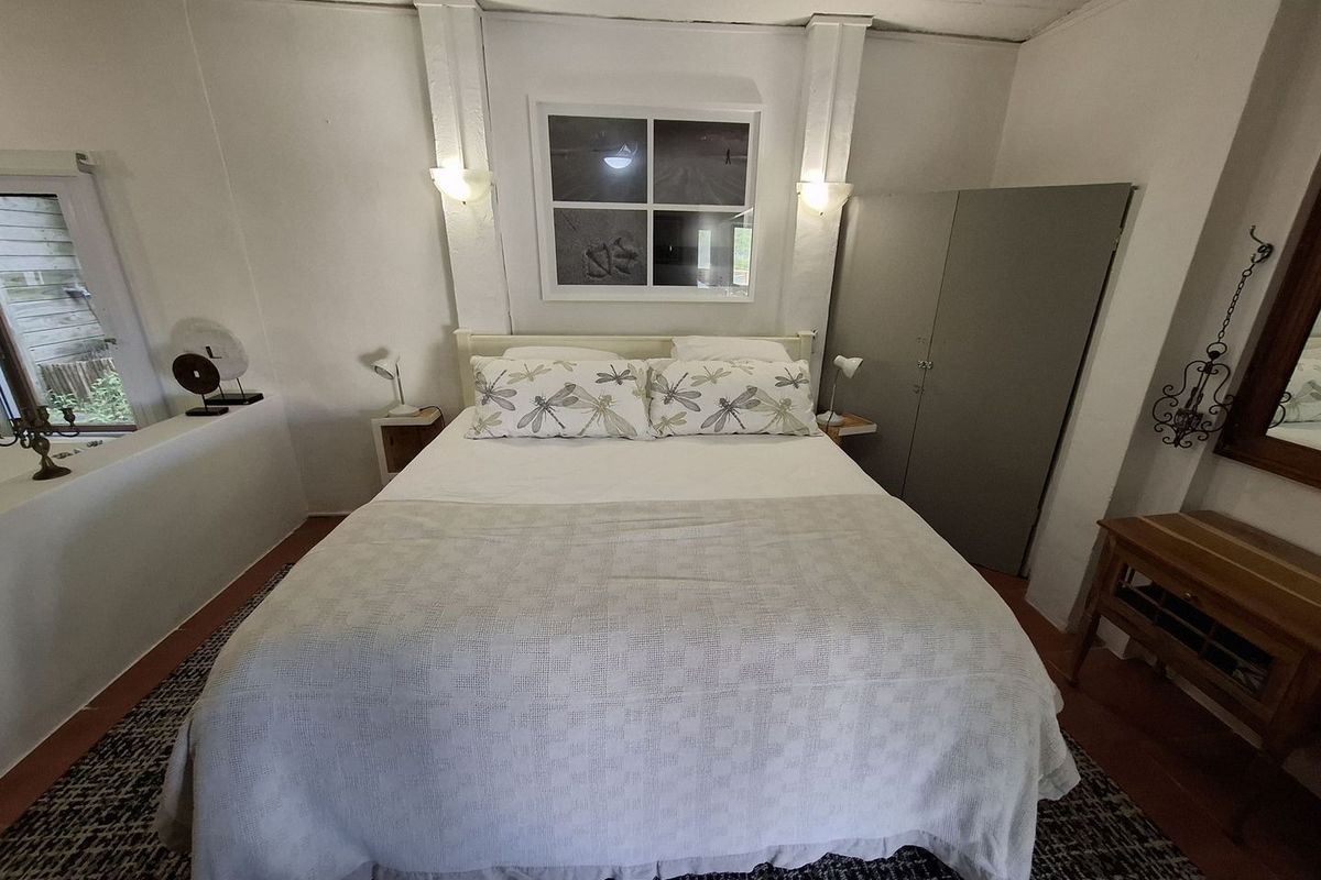 A bedroom featuring built-in cabinetry, wall-mounted lighting fixtures, and a window with a view of the exterior.