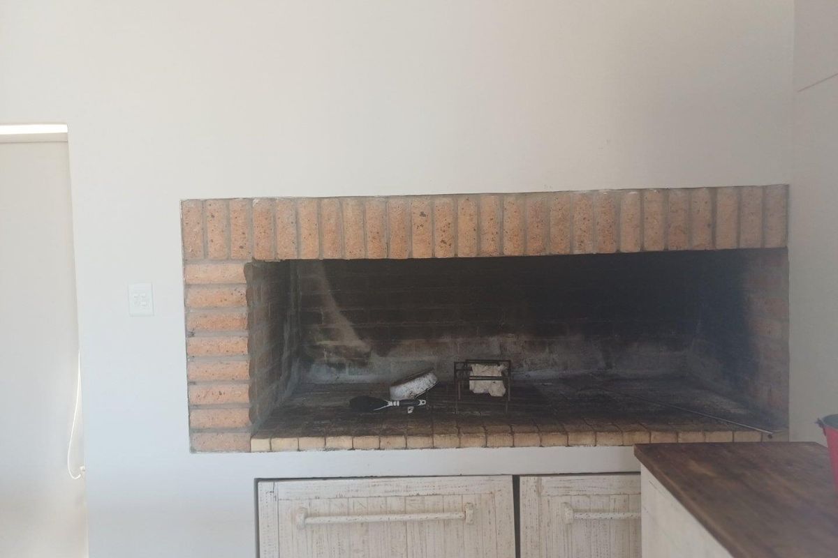 Built-in indoor brick fireplace or braai area featuring a rustic masonry surround and integrated lower storage cabinetry.