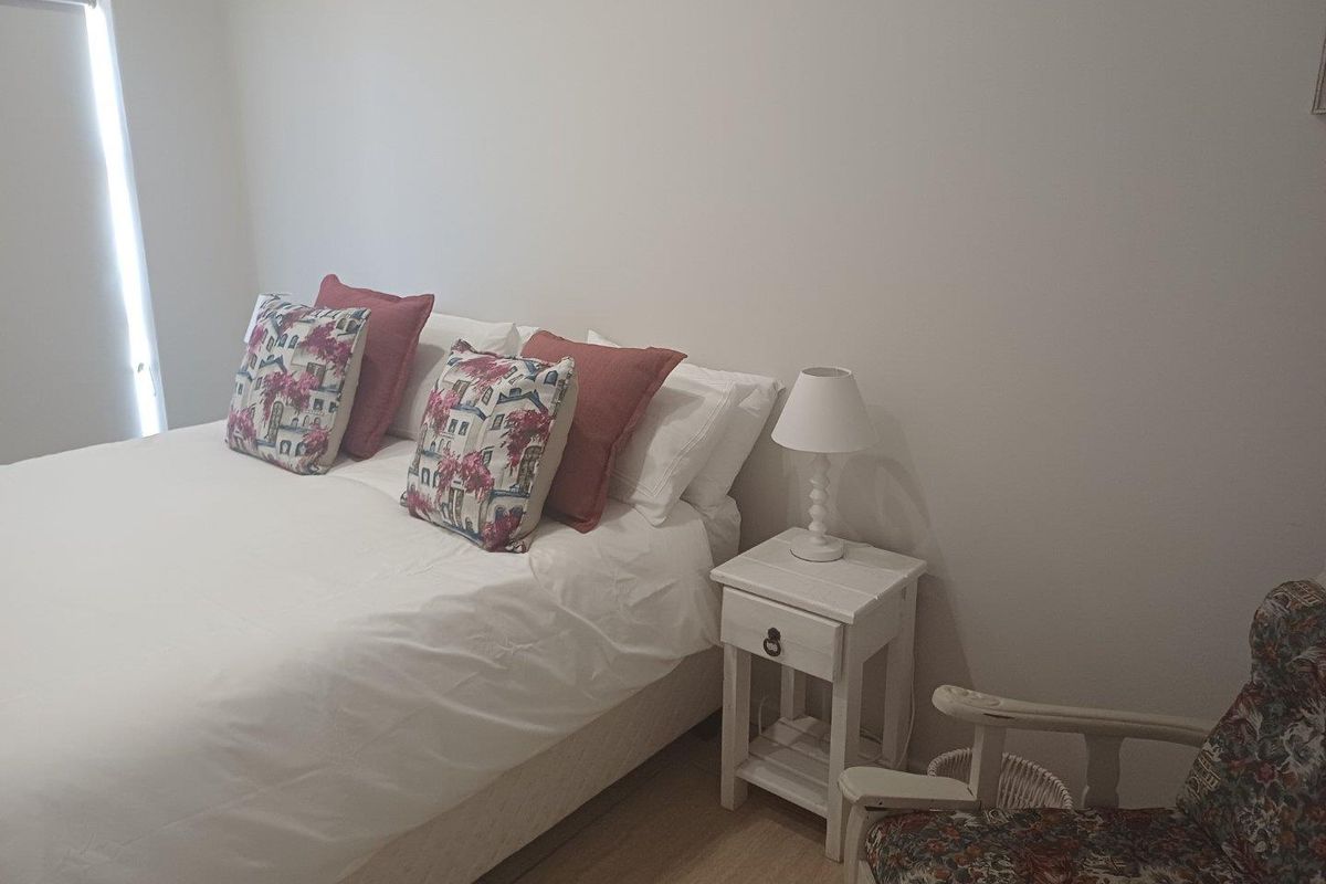A neutrally painted bedroom featuring tiled flooring and a window with a roller blind.